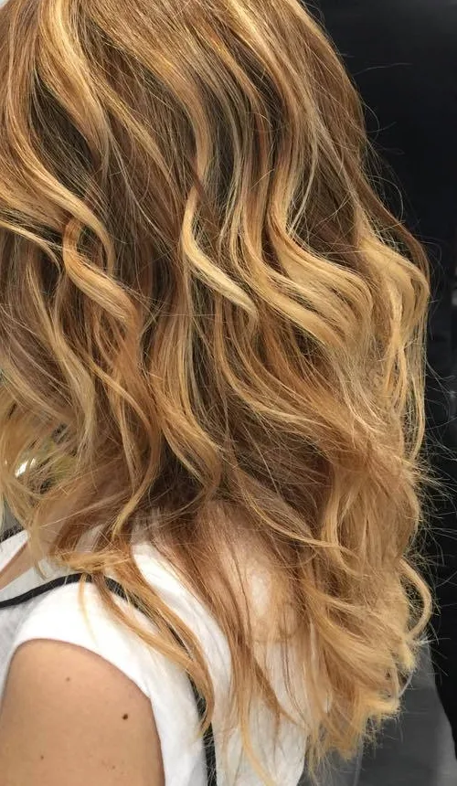 Shatush completato su capelli lunghi mossi, dal castano al biondo